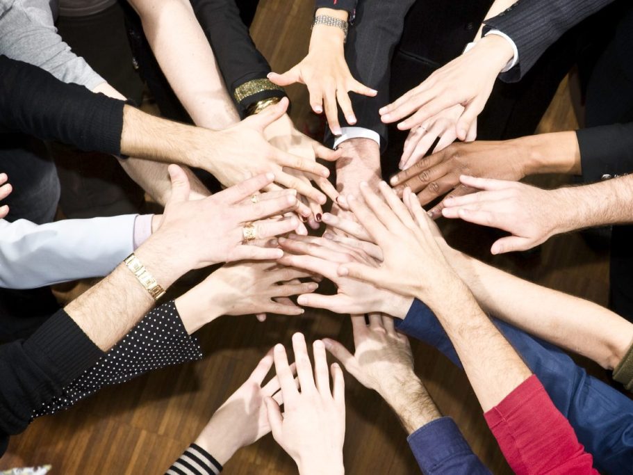 A diverse group of hands reaching toward each other, symbolizing collaboration and unity.